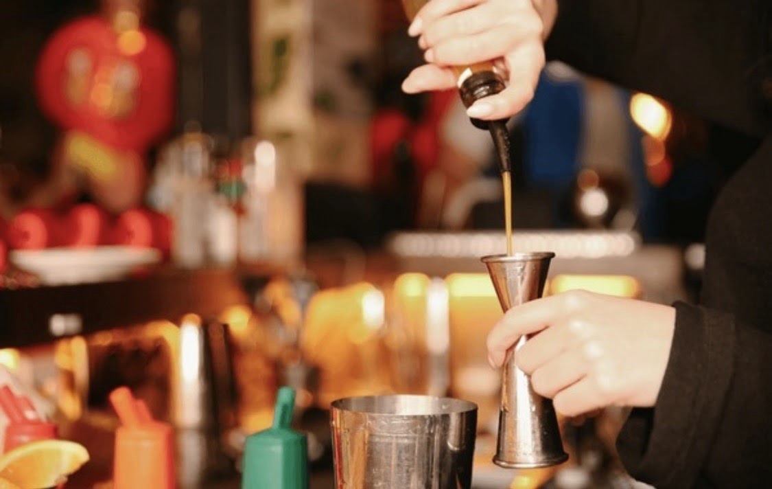 Close-up of cocktail ingredients being measured behind the bar